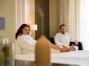Un uomo e una donna seduti su un letto in una stanza d'albergo di Mercure Gold Coast Resort a Gold Coast Altre 101 foto
