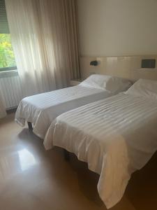 a bedroom with two beds with white sheets and a window at Albergo Casa dell'Ospite in Brescia
