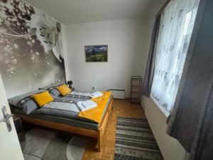a bedroom with a bed with yellow pillows and a window at Park apartman Kertes ház a park mellett gyönyörű kilátással Dog friendly garden house with a wonderful view next to the park in Murau