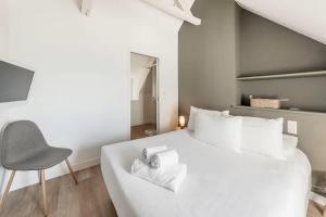 ein Schlafzimmer mit einem weißen Bett und einem Stuhl in der Unterkunft Bord De L'Eau 3 et 6 in Cancale