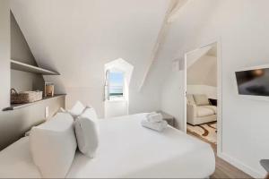 ein weißes Schlafzimmer mit einem weißen Bett und einem Spiegel in der Unterkunft Bord De L'Eau 3 et 6 in Cancale