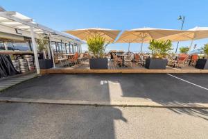 ein leerer Parkplatz mit Tischen, Stühlen und Sonnenschirmen in der Unterkunft Bord De L'Eau 3 et 6 in Cancale