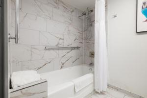a bathroom with a white tub and marble walls at Verta Hotel McAllen Airport in McAllen +13 photos