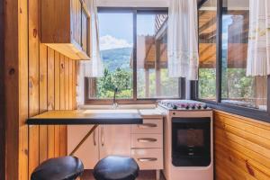 a kitchen with a stove and a sink and a window at Refugio Macacu com Vista para Montanhas in Siriú