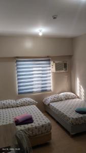 1 Schlafzimmer mit 2 Betten und einem Fenster mit Heizung in der Unterkunft Sunvida Cebu in Cebu City