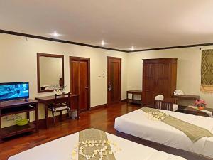 a bedroom with two beds and a desk and a television at Luang Prabang Residence - The Boutique Villa in Luang Prabang