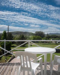 a white table and chairs on a deck with a view at Altos de Ventana in Sierra de la Ventana