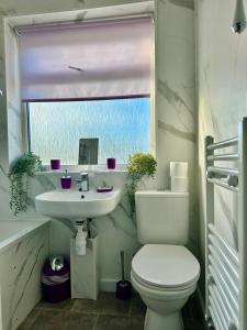 Un baño con inodoro, lavabo y ventana. en Enfield Contractor Base With Games Room, en Brimsdown Station