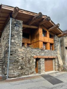 un bâtiment en pierre avec un toit en bois dans l'établissement Chalet des balcons, à Saint-Michel-de-Maurienne