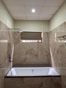 Un baño con bañera y ventana. en Le SAFFRON, en Padinjarathara