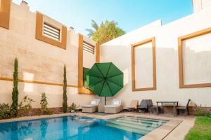 a pool with a green umbrella next to a house at Aurora sky view suite in Sheikh Zayed