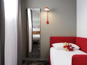 un osito de peluche sentado en una cama en una habitación de hotel en ibis Styles Chartres Métropole, en Chartres