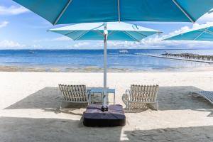 two chairs and a table with an umbrella on the beach at Dominiks pink dream Studio Balcony Ocean View Balcony Fast-Wifi at Tambuli Resort High Floor in Maribago