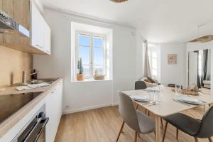 a white kitchen with a table and chairs in a room at Bord de l'Eau 4 in Cancale +2 photos