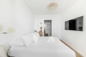 a white bedroom with a bed and a tv at Bord de l'Eau 4 in Cancale