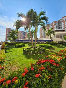 a park with flowers and a palm tree and buildings at Espectacular Apto de 3 Habitaciones con piscina y parqueadero gratuito excelente relacion calidad precio in Girardot