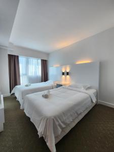 a hotel room with three beds with white sheets at Comfy En-Suite Room in Kota Kinabalu