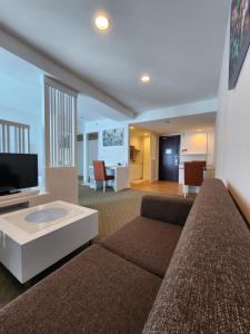 a living room with a couch and a tv at Comfy En-Suite Room in Kota Kinabalu