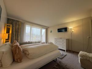 Un dormitorio con una cama y una cómoda y una ventana. en Apartment with great view at Residence Brunner, en Wengen