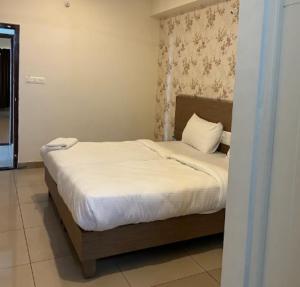 a bedroom with a bed with white sheets and pillows at Hotel Janani Mansion in Mysore