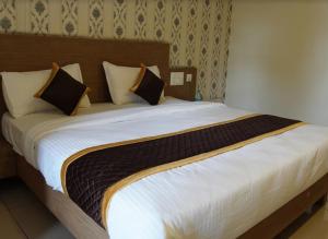 a bedroom with a large bed with white sheets and pillows at Hotel Janani Mansion in Mysore +4 photos