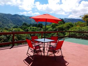 a table with chairs and an umbrella on a balcony at Cabañas El Amanecer in Cuetzalán del Progreso +17 photos