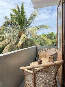 a balcony with two chairs and a table and a palm tree at Olaia Apartments and Cafe in Weligama
