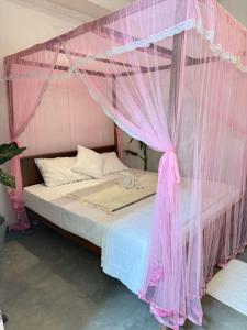 a pink canopy bed with pink mosquito netting at Olaia Apartments and Cafe in Weligama