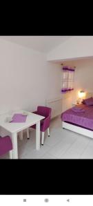 a room with a white table and purple chairs at Apartman Tamara i Tijana in Škaljari +16 photos