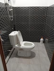 a bathroom with a toilet and a black tiled wall at ibilik Changloon in Changlun
