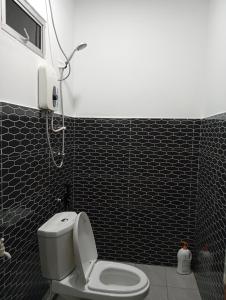 a bathroom with a toilet and a phone on the wall at ibilik Changloon in Changlun
