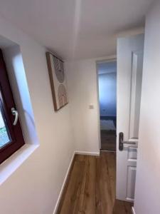 Dieses weiße Zimmer verfügt über einen Flur mit einer Tür und Holzböden. in der Unterkunft Soh Rent Appartement Schiltigheim proche Strasbourg terrasse -Tv in Schiltigheim