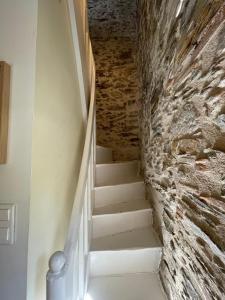 a stairway with a stone wall and white stairs at Maison indépendante cosy avec terrasse privée - La Laiterie in Nantes