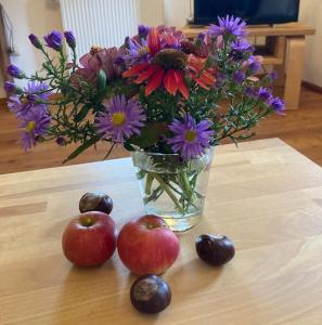 a vase with flowers and apples on a table at Ferienwohnung Koppelblick in Pfarrweisach