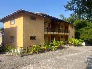 un edificio amarillo con un montón de plantas delante de él en Estúdio com piscina, en Trancoso
