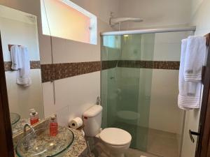 Un baño con inodoro y ducha de cristal. en Estúdio com piscina, en Trancoso