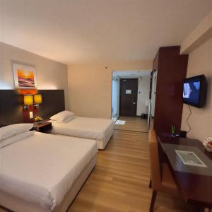 a hotel room with two beds and a flat screen tv at Ming SCSP Tweenie Suites in Kota Kinabalu +3 photos