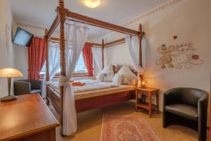 a bedroom with a canopy bed with a desk and a chair at Hotel Am Eifelsteig in Neroth