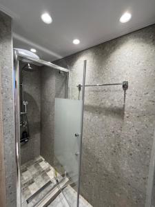 una ducha con puerta de cristal en un baño en AA seaside apartment, en Artemida