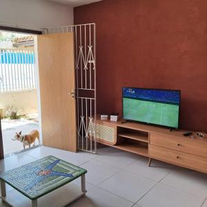 un salon avec une télévision sur un centre de divertissement en bois dans l'établissement Casa Bacutia, à Guarapari 8 autres photos