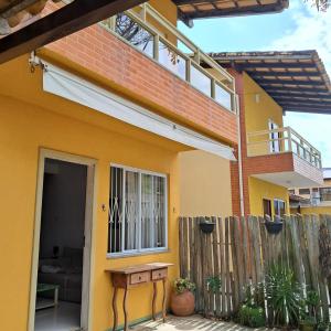 une maison jaune avec une clôture devant elle dans l'établissement Casa Bacutia, à Guarapari