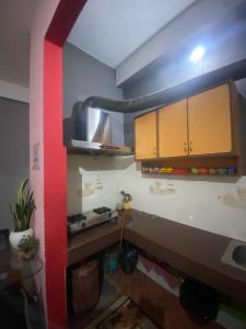 a kitchen with brown cabinets and a red wall at Haven Stay in Dibrugarh