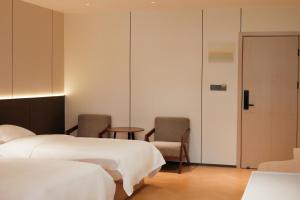 广州HuaHang Hotel - Free Shuttle&Free Breakfast - Guangzhou Baiyun International Airport的一间有两张床、一张桌子和几把椅子的酒店房间 更多20张照片