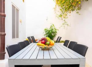 een fruitschaal op een tafel met stoelen bij Villa Luciano - Rooftop Jacuzzi, BBQ, Billiards & Steps from Sea in Sliema +29 foto's