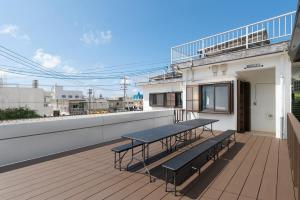 a balcony with a table and benches on a building at 一棟貸しハウスまれち in Kumejima