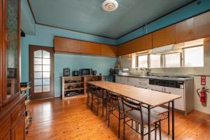 a large kitchen with a wooden table and chairs at 一棟貸しハウスまれち in Kumejima