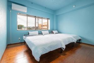 a large bed in a blue room with a window at 一棟貸しハウスまれち in Kumejima