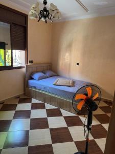ein Schlafzimmer mit einem Bett und einem Ventilator auf dem Boden in der Unterkunft Maison familiale 2 chambres salon marocain in Tiznit