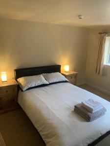 a bedroom with a bed with white sheets and two lamps at The Lord Nelson Inn in Marshfield