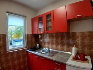 a kitchen with red cabinets and a sink at Apartmani RALE rooms in Sarajevo